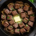 A cast iron skillet full of 15-minute steak and onions, a perfect example of easy steak dinner recipes.