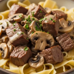 A comforting bowl of creamy leftover tri-tip beef stroganoff with mushrooms, served over wide egg noodles.